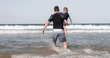 hombre en la playa con un niño en brazos